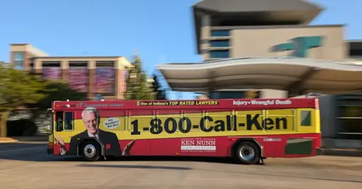 A bus with a full-wrap advertisement that mostly reads "1-800-Call-Ken"