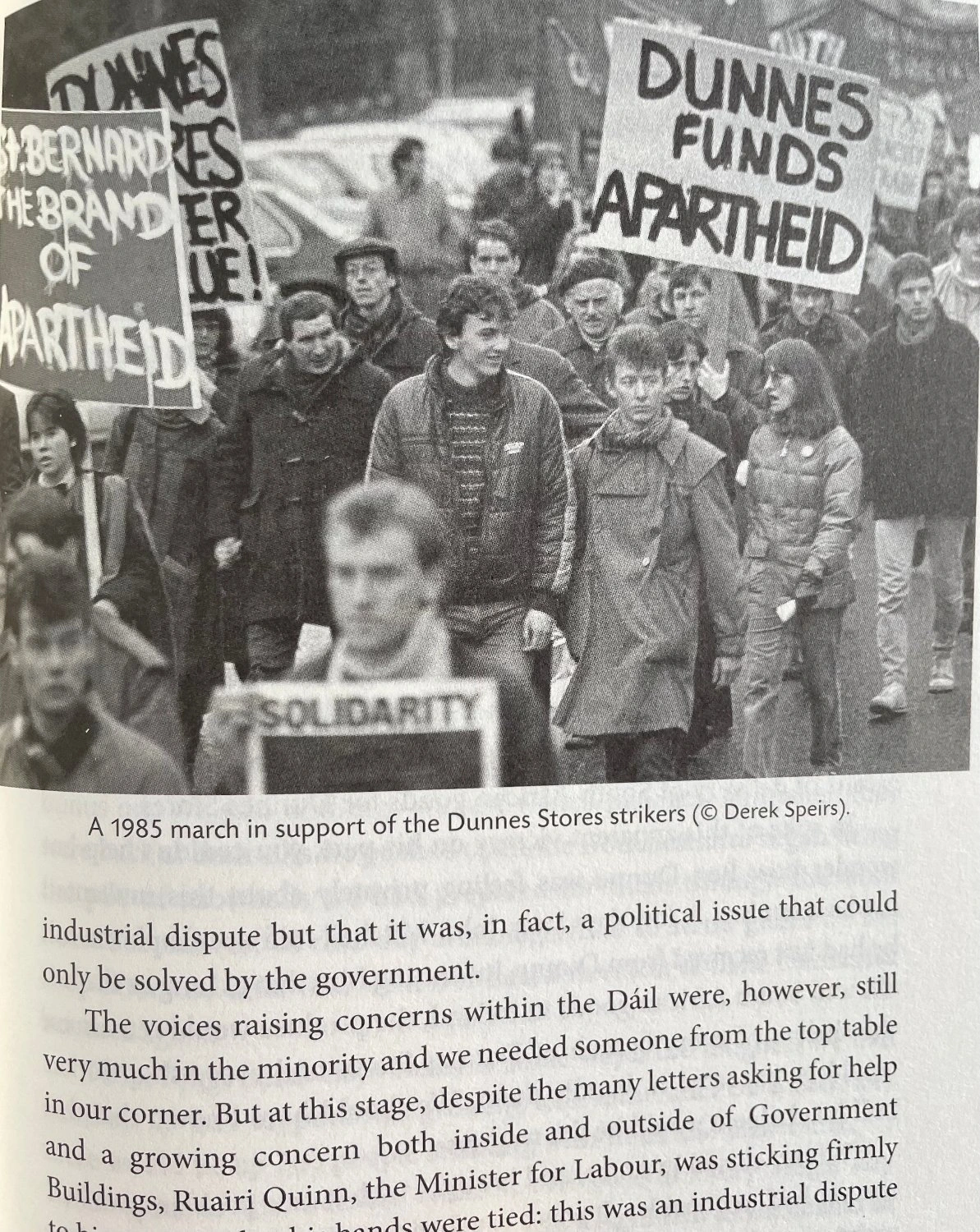 Protester hold signs saying "Dunnes Funds Apartheid" and similar messages.
