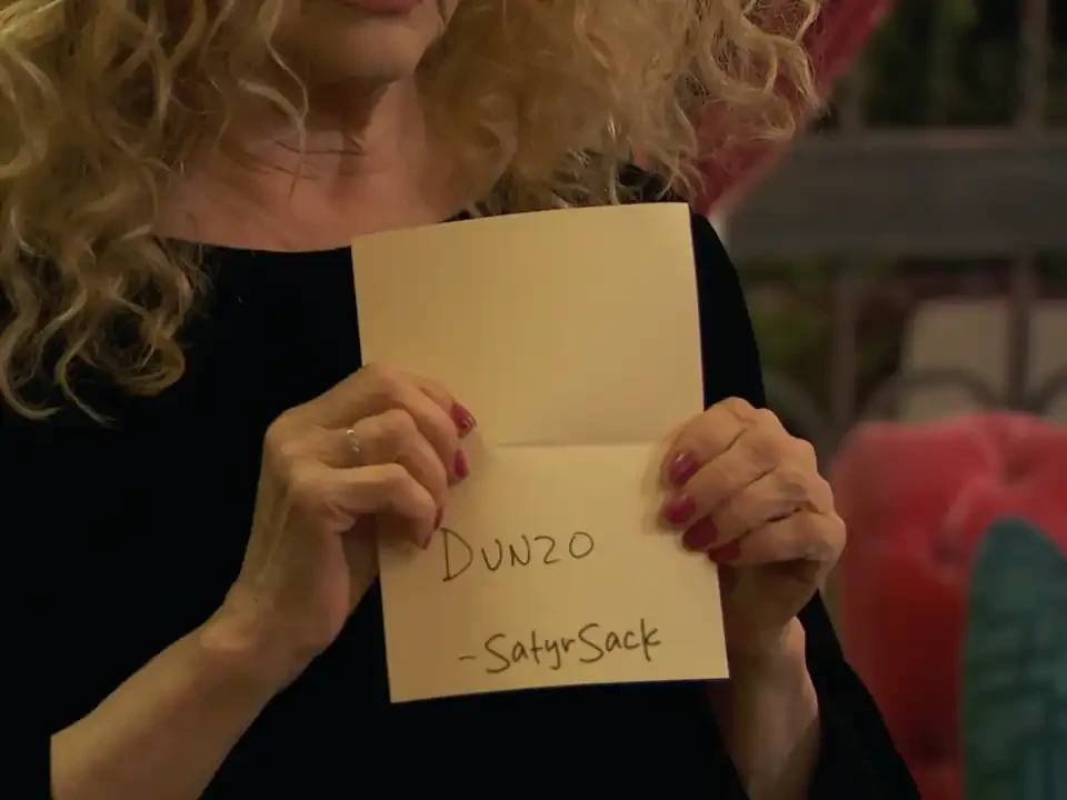 Sam holding a card with words handwritten on it reading "Dunzo -SatyrSack"